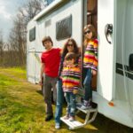 vacanze-in-famiglia-viaggi-in-camper-con-bambini-genitori-felici-con-bambini-in-viaggio-di-vacanza-in-camper