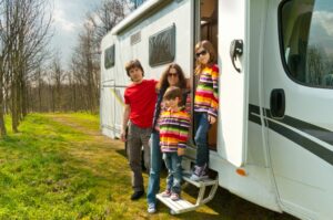 vacanze-in-famiglia-viaggi-in-camper-con-bambini-genitori-felici-con-bambini-in-viaggio-di-vacanza-in-camper